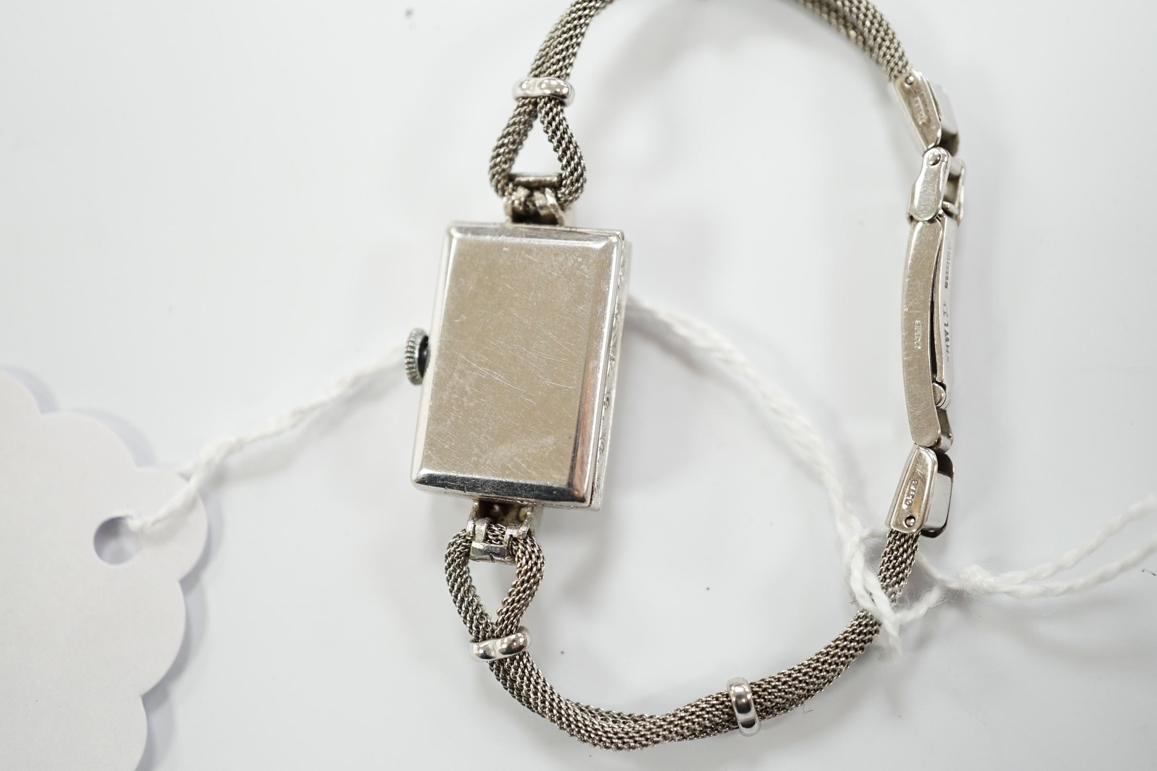 A lady's white metal and diamond set rectangular dial manual wind cocktail watch, on a 9ct white gold, bracelet, gross weight 17.4 grams.